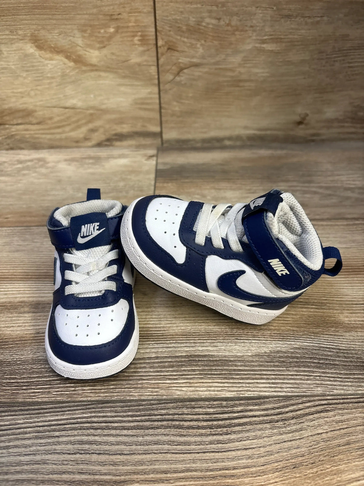 Front and side view of Nike Court Borough Mid 2 TD sneakers showcasing white and Signal Blue panels and straps on wood surface