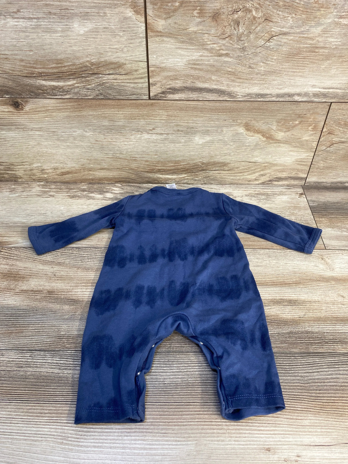 Navy blue long sleeve baby romper with tie dye pattern, displayed on wood background