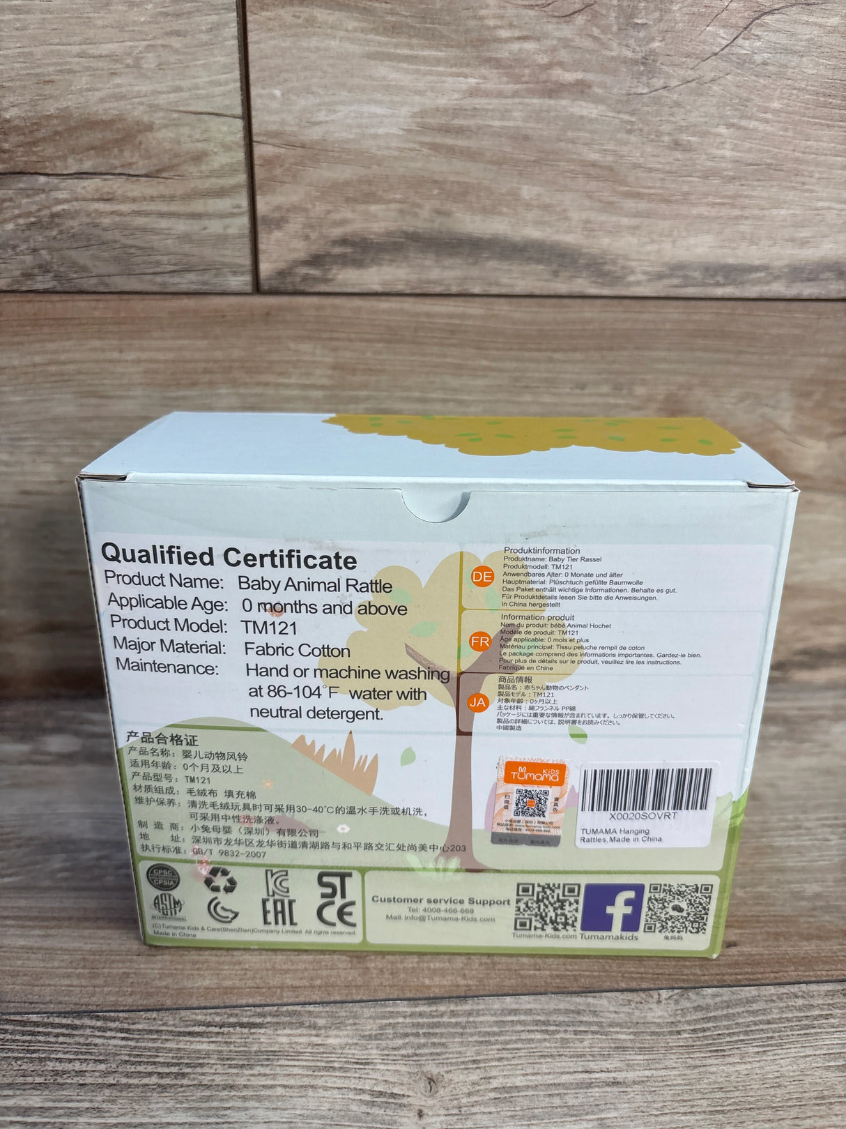 Rear view of Tumama Hanging Animal Rattles 4pk box showcasing the headline Qualified Certificate and product information text on a wooden surface