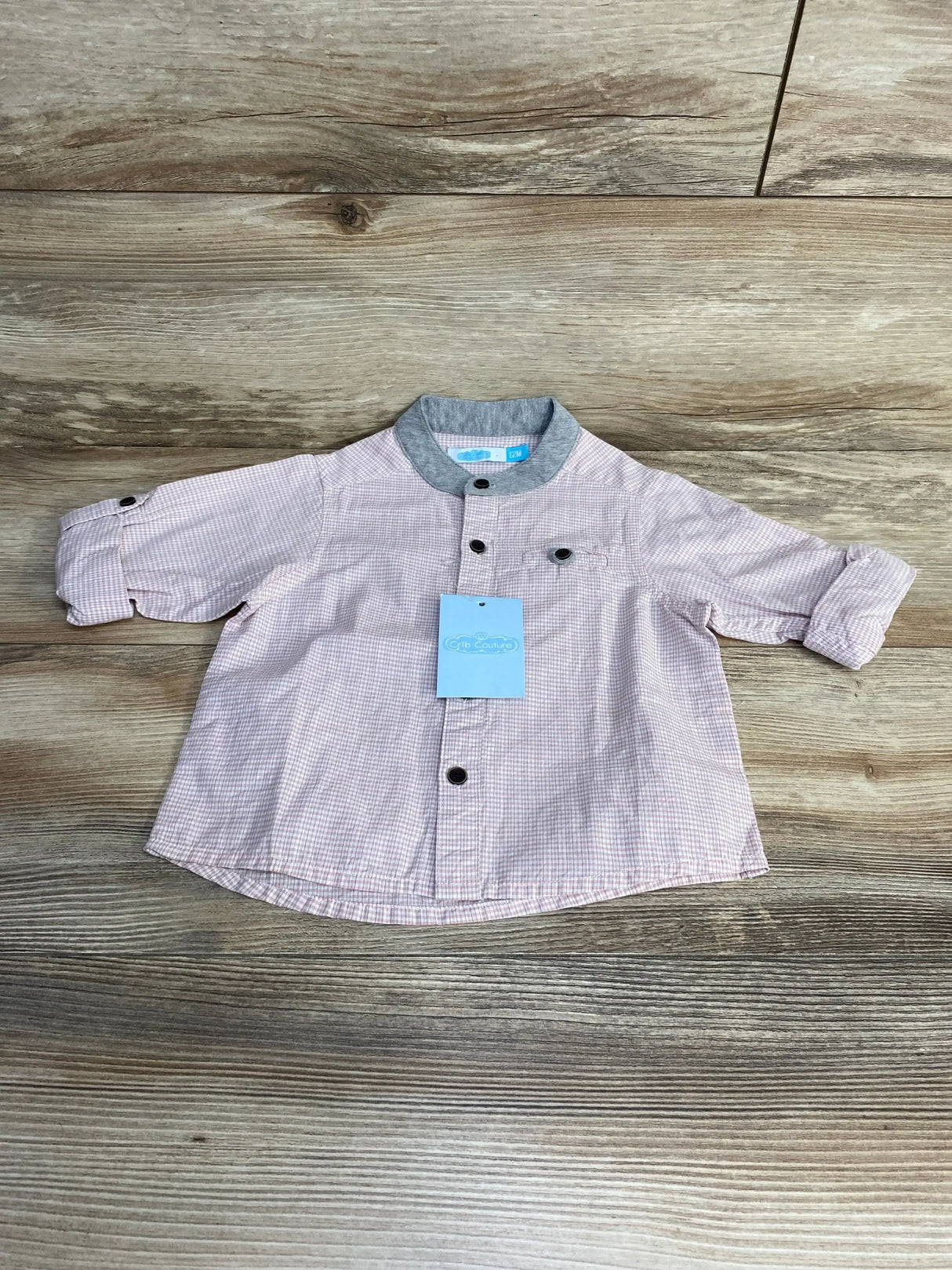 Front flat lay of pink Crib Couture button-up shirt size 12M showing gray collar and roll-tab sleeves on wood background