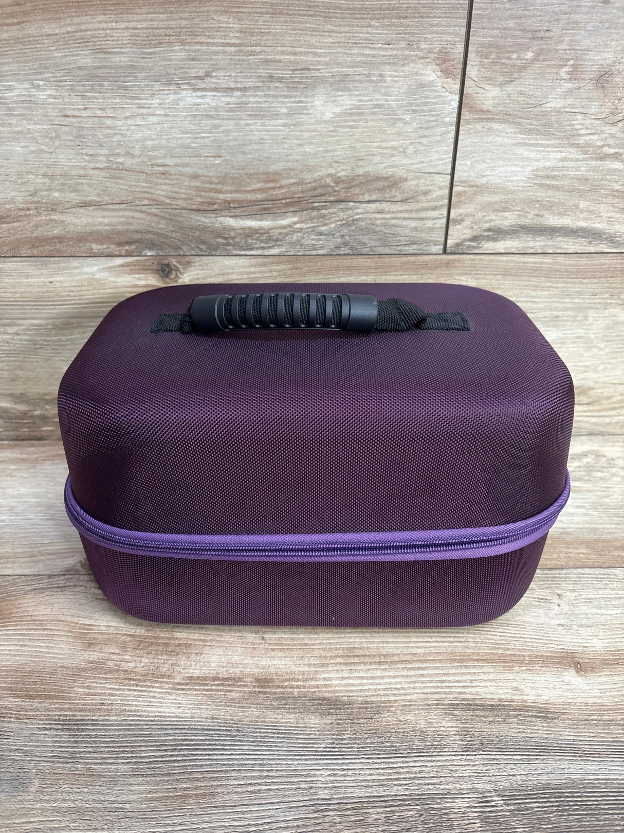 Front view of Hermitshell hard EVA travel case for Spectra double/single breast pump showcasing purple textured shell and black molded handle on wood background