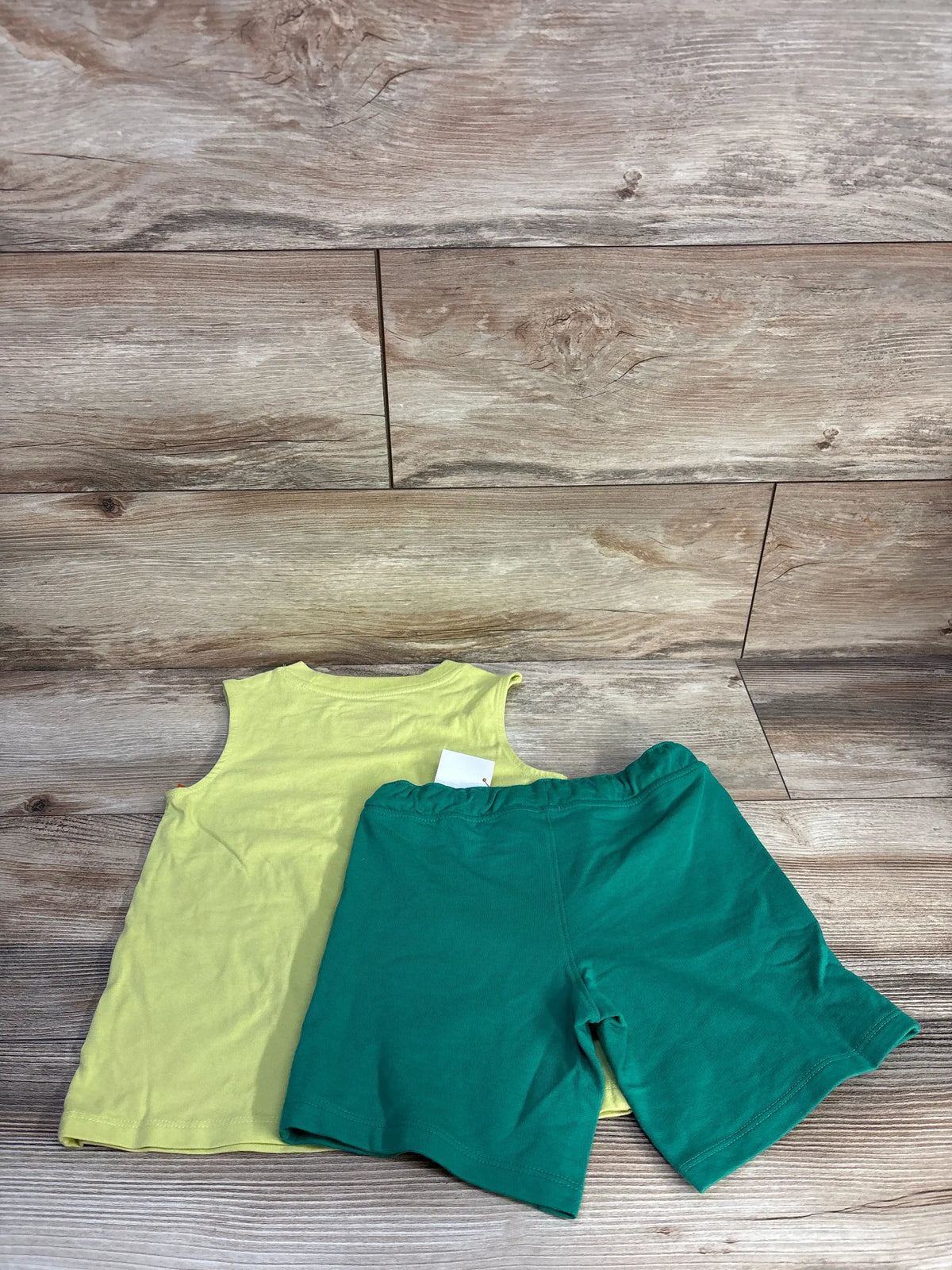 Top-down view of Cat and Jack 2pc tank top and shorts set in size 4T, showing lime green tank top and drawstring shorts on wood flooring