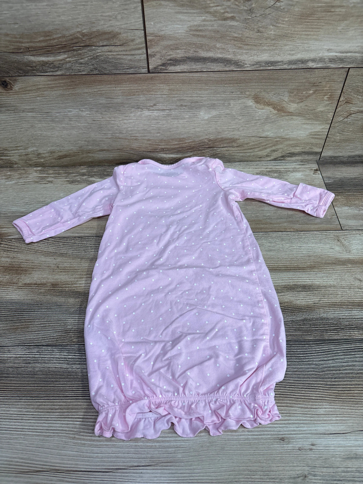 Front view of Little Me pink polka dot sleep gown showcasing long sleeves and ruffled hem on a wood-look floor