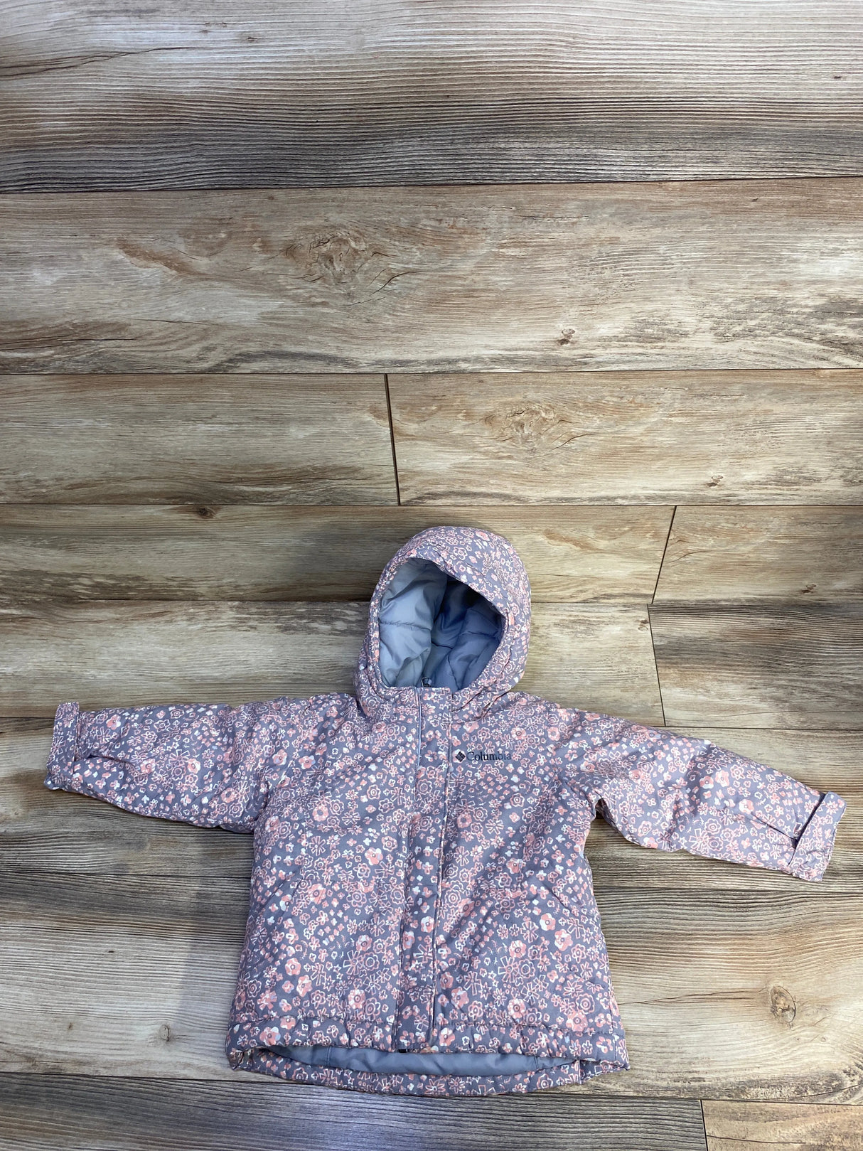 Pink floral children's hooded winter jacket on wood floor