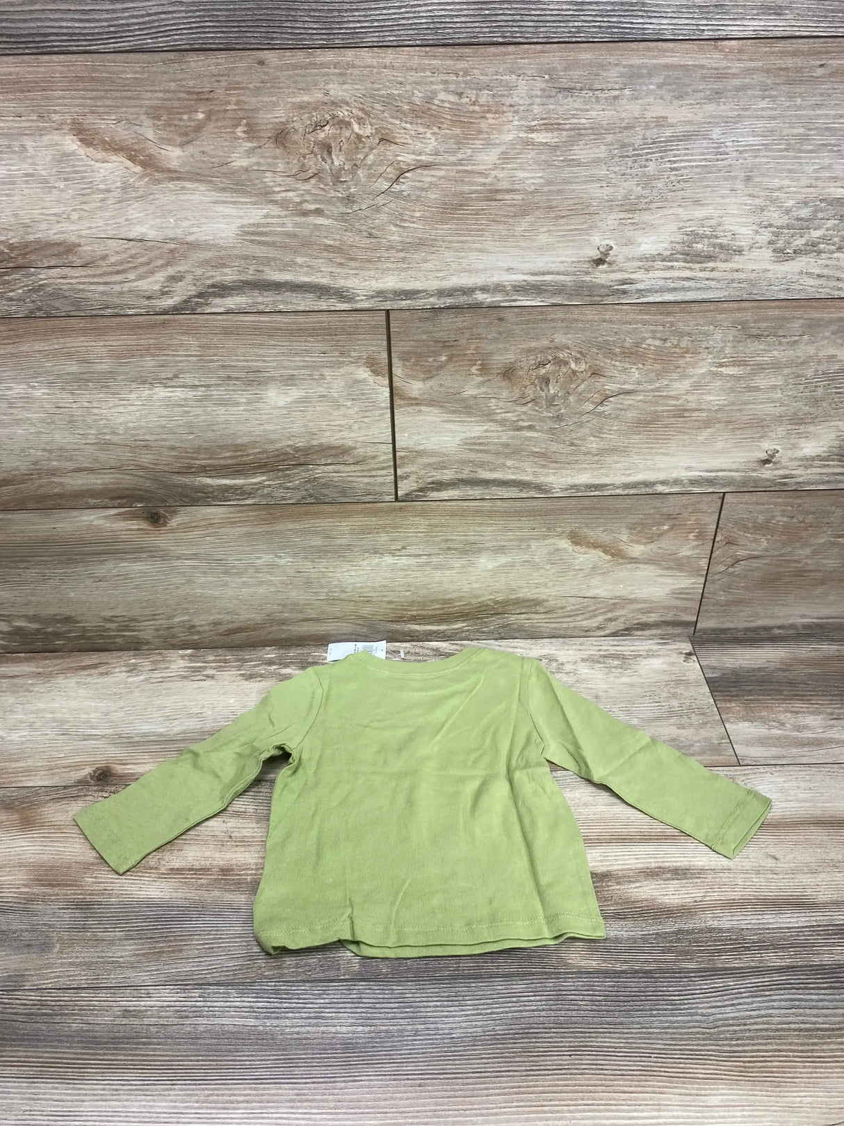 Back view of Old Navy green long sleeve shirt showcasing solid color and hangtag at neckline on wood plank floor