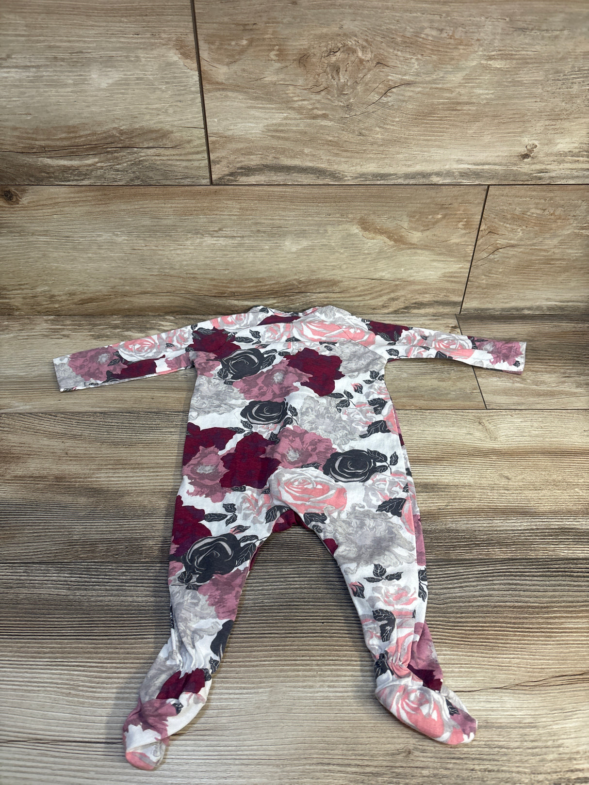 Baby floral footed onesie with pink, red, and gray roses on wood floor