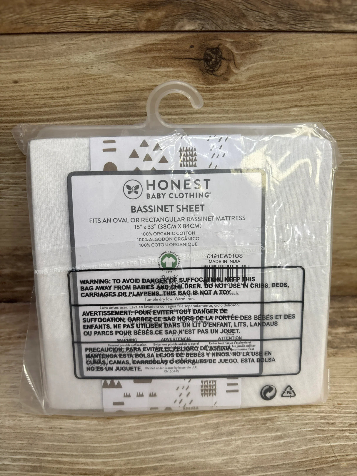 Front view of Honest Baby organic cotton bassinet sheet in packaging showing brand label and 15 x 33 size on wood