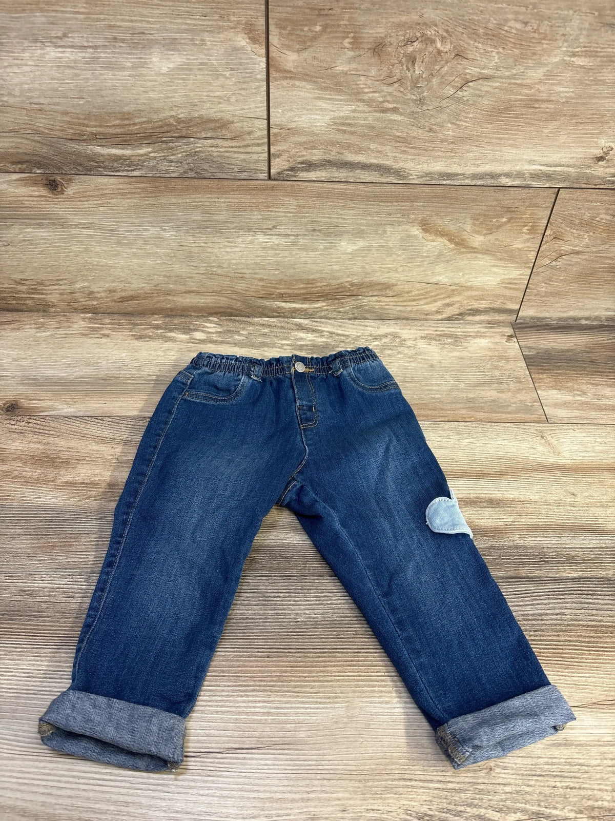 Front view of Mayoral newborn blue jeggings showcasing an elasticated waistband and rolled cuffs on a wood-look floor