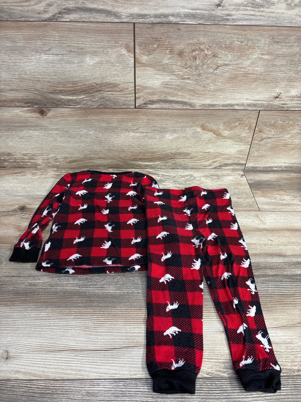 Children's red and black buffalo plaid pajama set with white moose print on wood floor