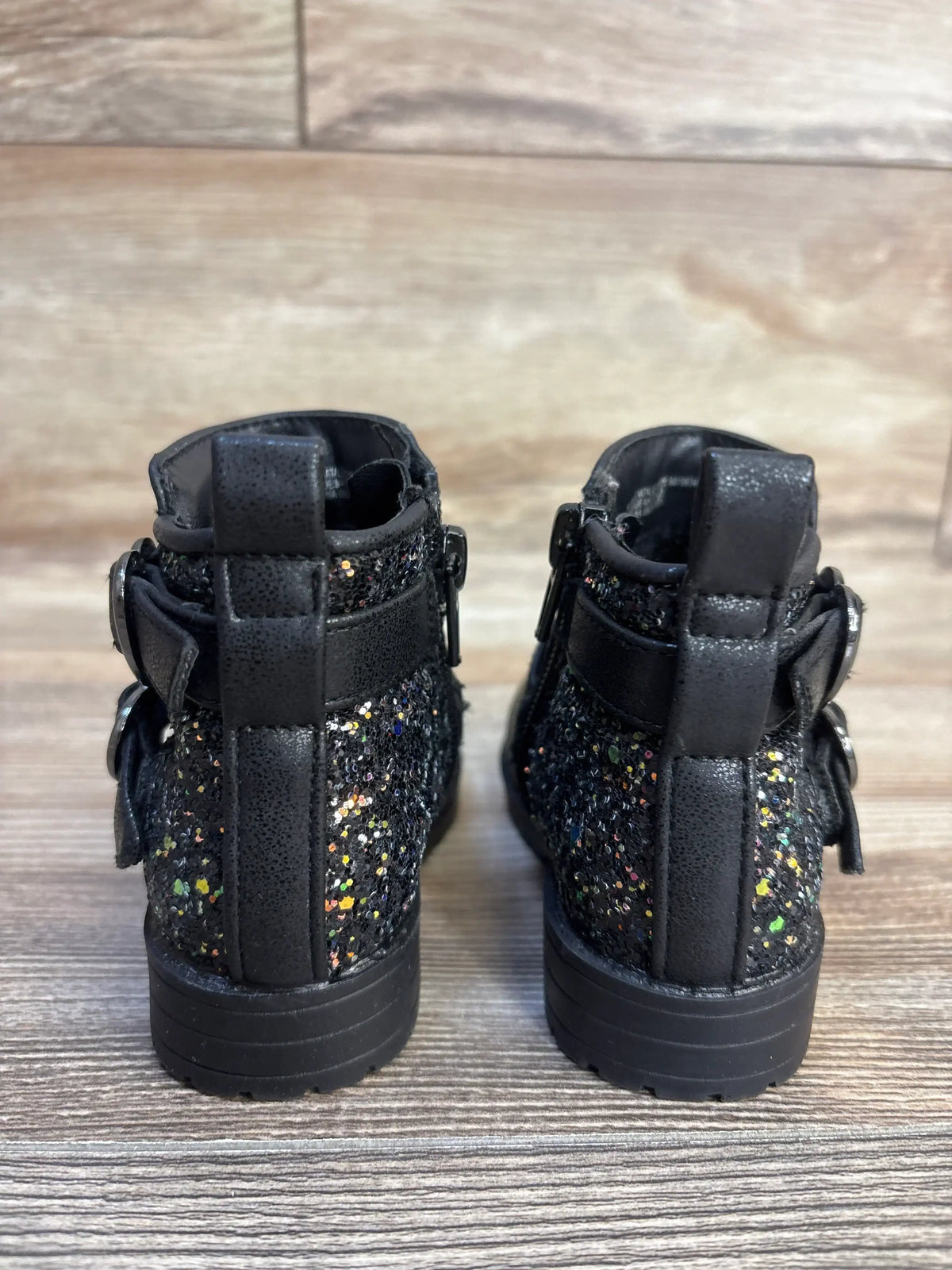 Black glitter toddler boots with buckles, kids' fashion footwear on wood floor
