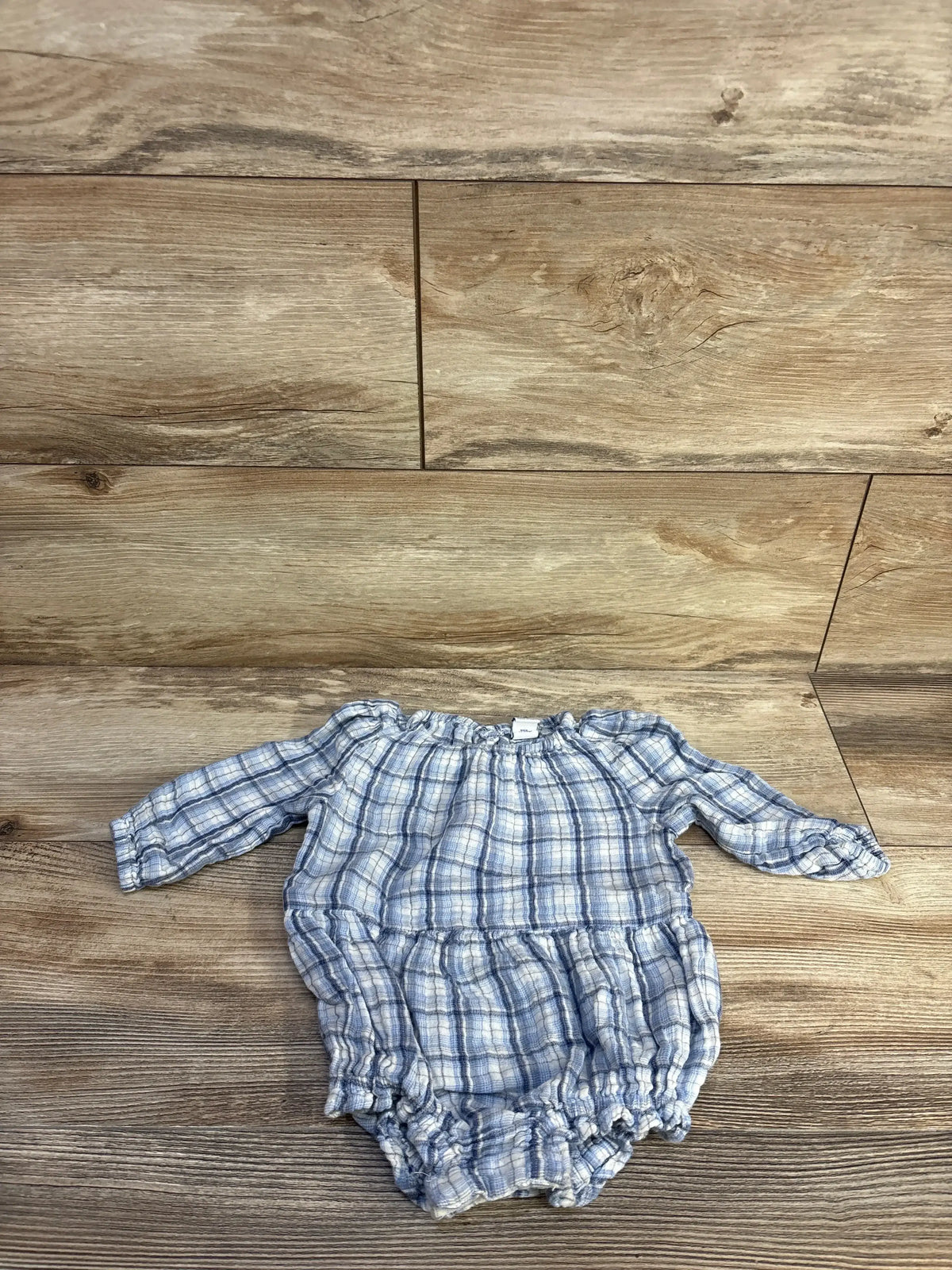 Flat lay of blue plaid Old Navy bubble romper 6-12M showing long sleeves and elastic leg openings on wood background
