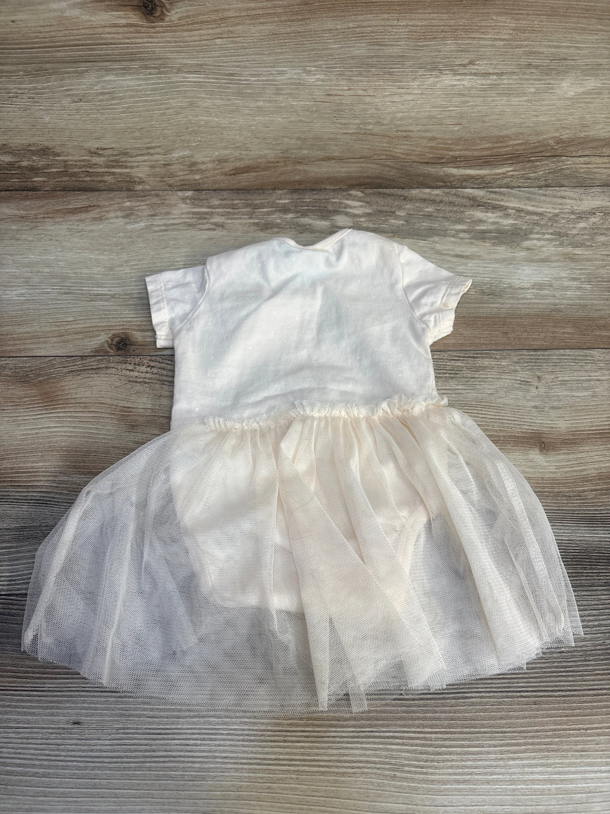 Back view of Disney Baby Winnie the Pooh cream tulle bodysuit dress (3-6 months) showing short sleeves and layered tulle skirt on wood background