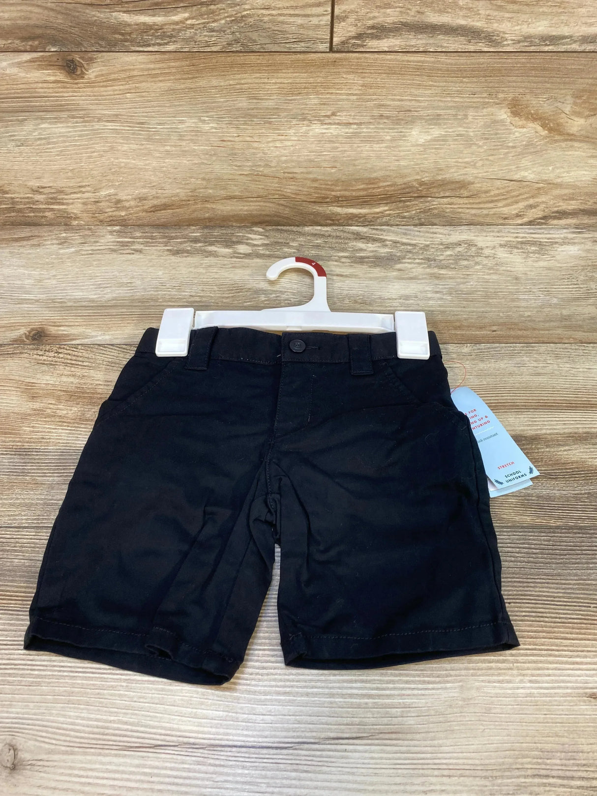 Front view of Cat & Jack toddler black school uniform shorts showing button closure and front pockets on a wood-grain background