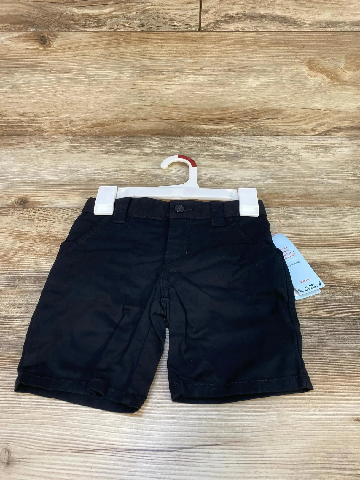 Front view of Cat & Jack toddler black school uniform shorts showing button closure and front pockets on a wood-grain background