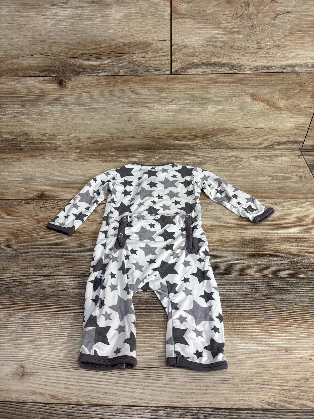 Back view of white baby romper with gray star pattern and dark gray trim on wooden floor