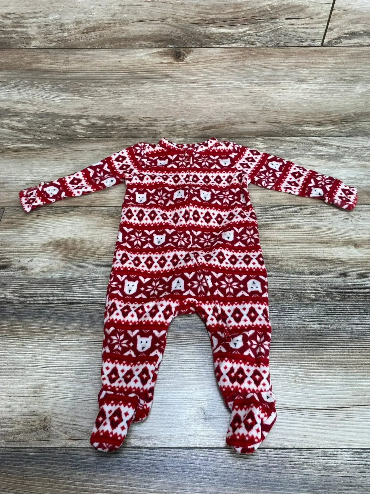 Red Fair Isle baby sleeper (3-6M) showing polar bear print, front zipper and footed legs on wood background