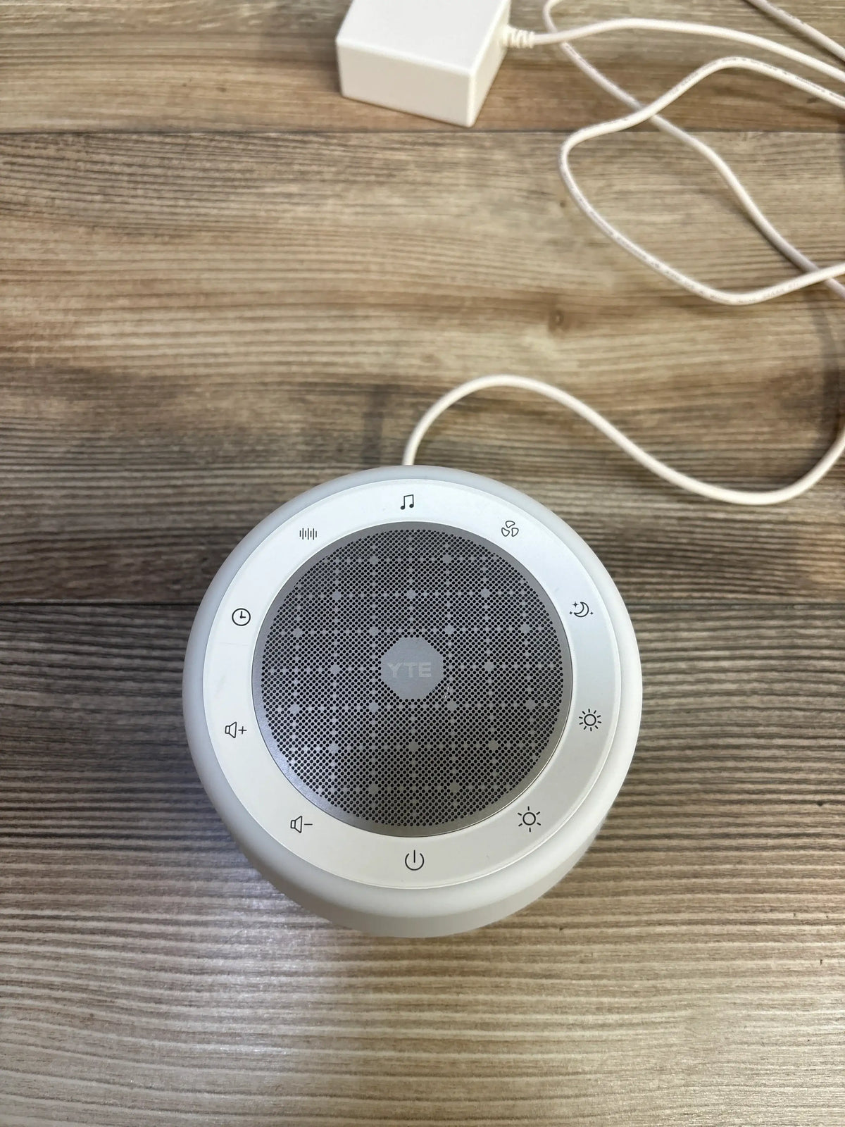 YTE TP1 white noise sound machine on a wooden surface with power adapter