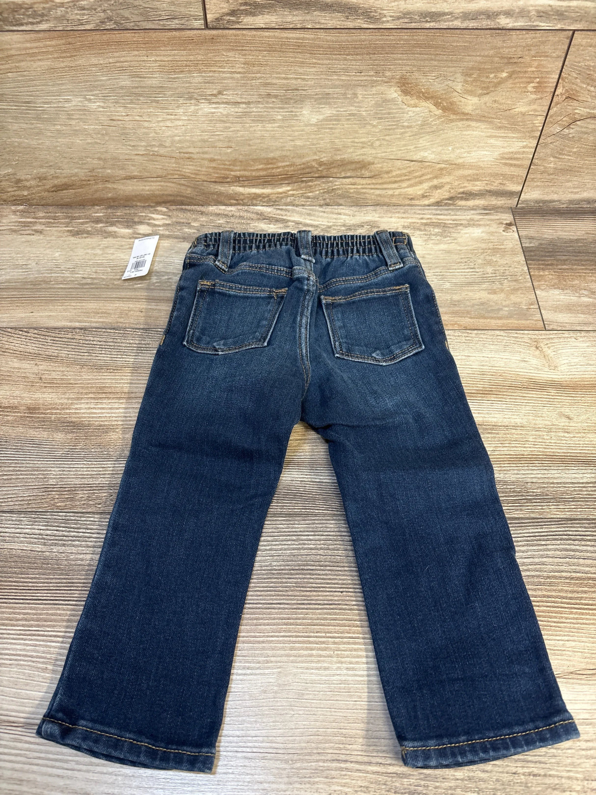 Kids dark blue denim jeans with elastic waistband, shown flat on wooden background