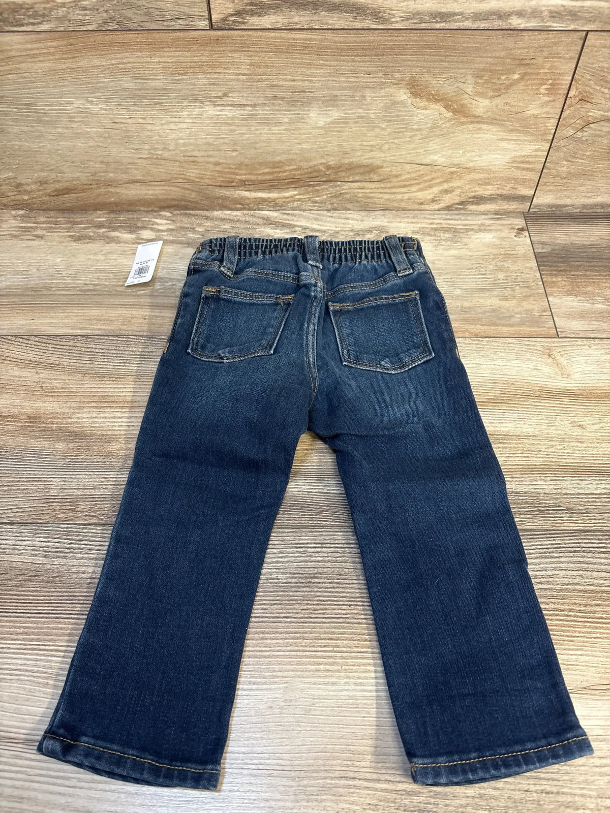 Kids dark blue denim jeans with elastic waistband, shown flat on wooden background