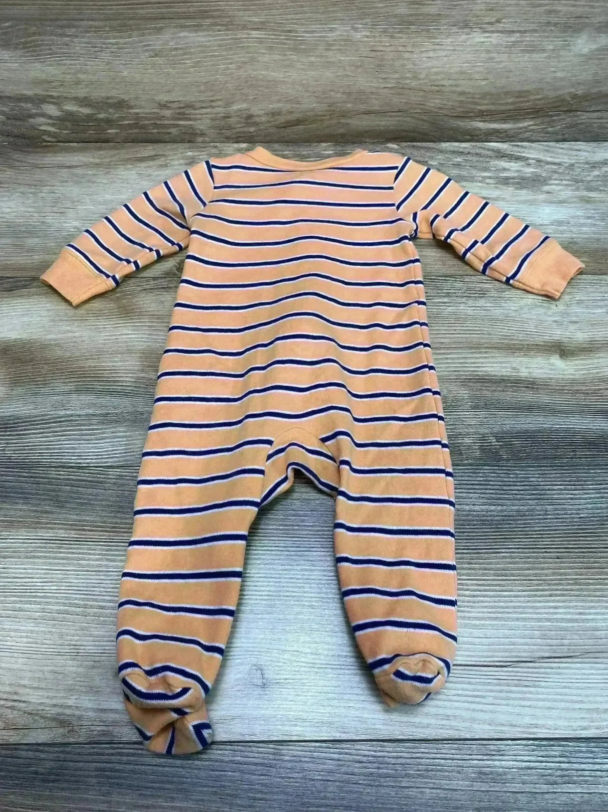 Flat lay of Carter's orange striped footed sleeper showcasing long sleeves and built in feet on wood plank background