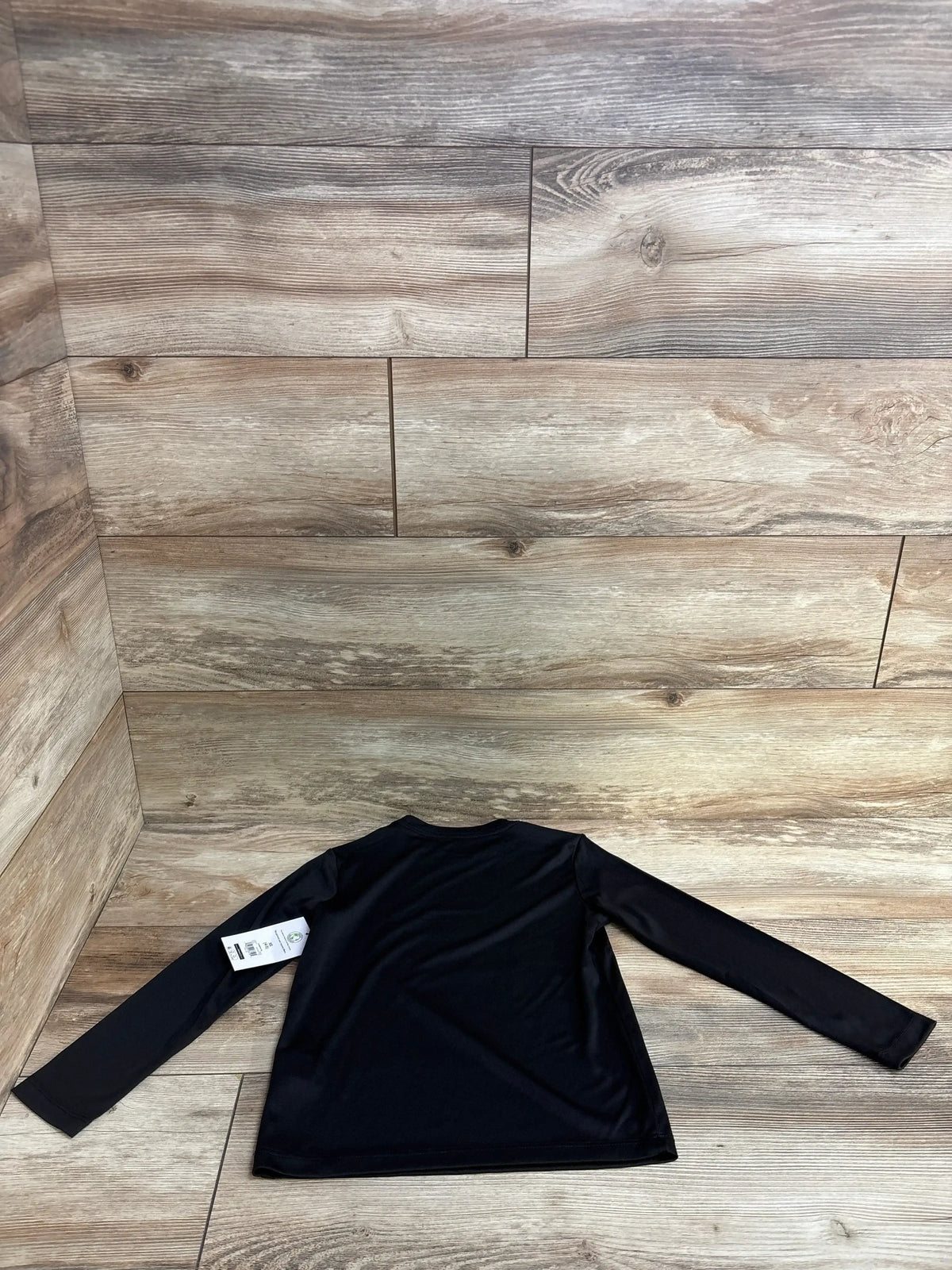 Black long sleeve shirt with tag on wood background, flat lay product photo