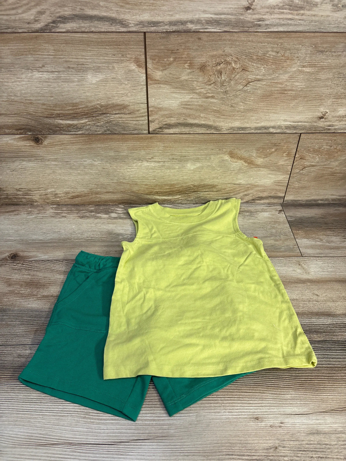 Top-down view of Cat & Jack 2-piece tank top and drawstring shorts set in lime green and dark green on a wood background