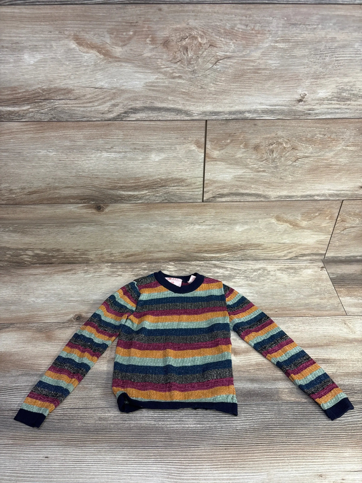 Flat lay of 4T Scotch and Soda metallic striped pullover with multicolor stripes and navy cuffs on light wood floor