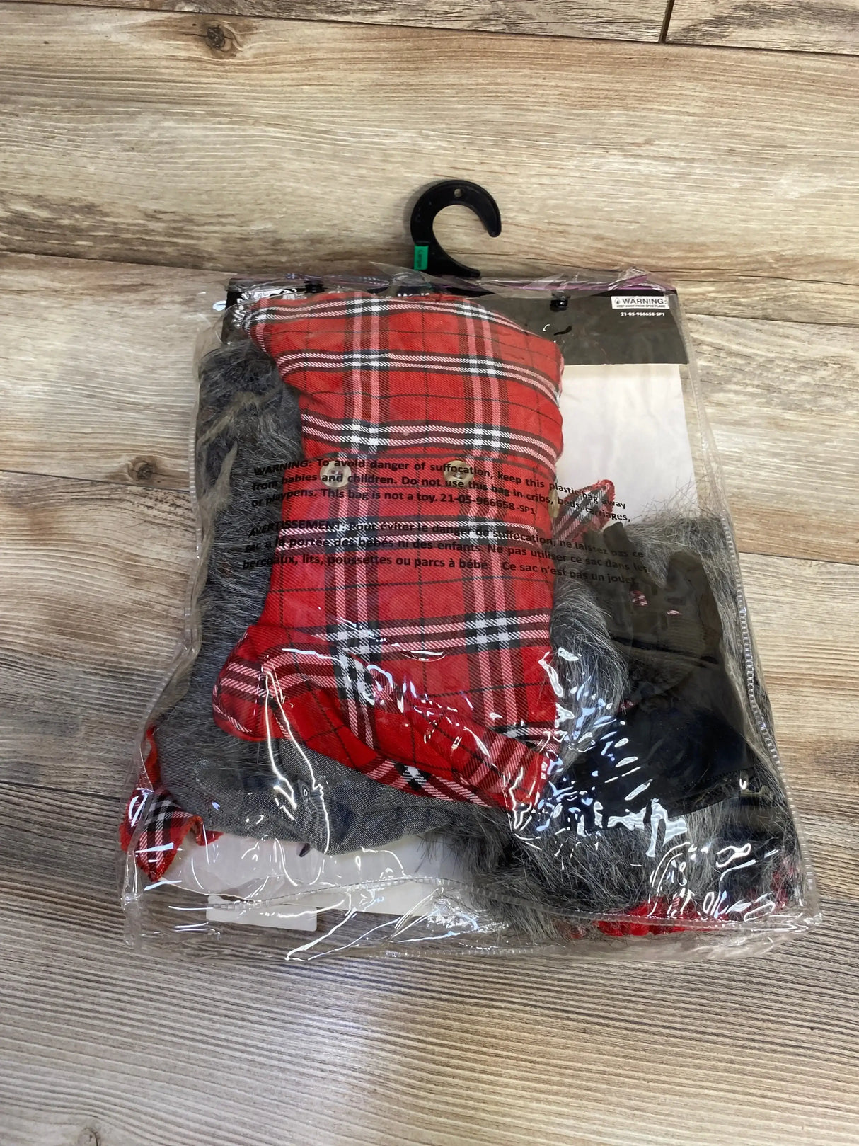 Front view of red Charming Werewolf costume showcasing plaid fabric and faux fur in clear packaging on a wood floor