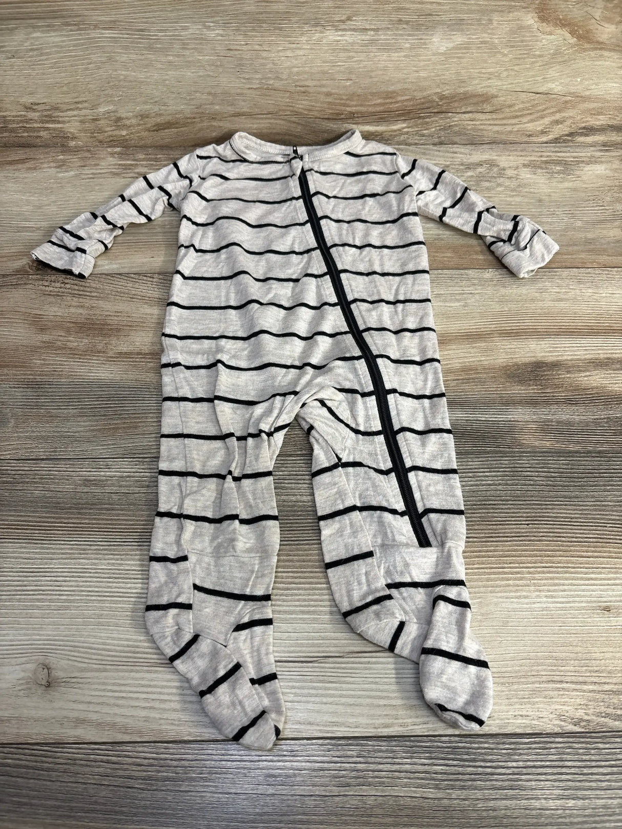 Front view of baby grey striped footie showcasing diagonal black zipper, long sleeves, and built-in feet on wood floor