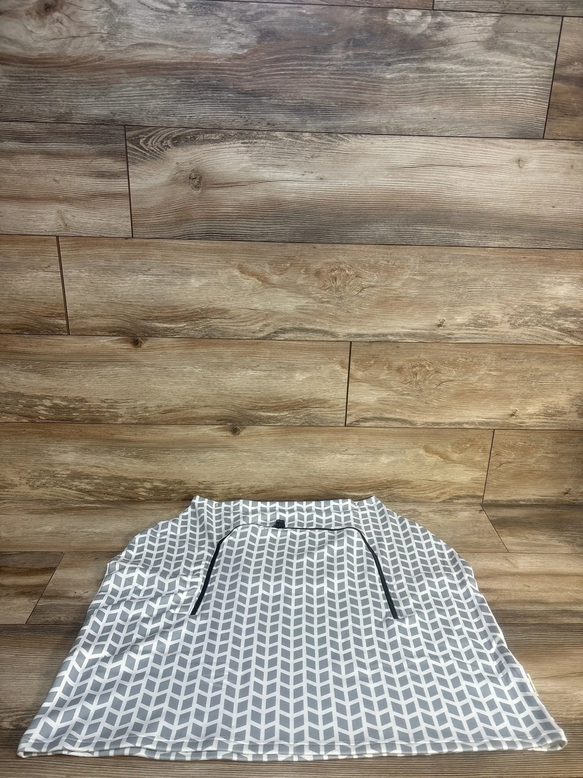 Flat lay of KeaBabies Warmzy car seat cover, gray kite chevron pattern, full coverage with elastic strap on wood floor