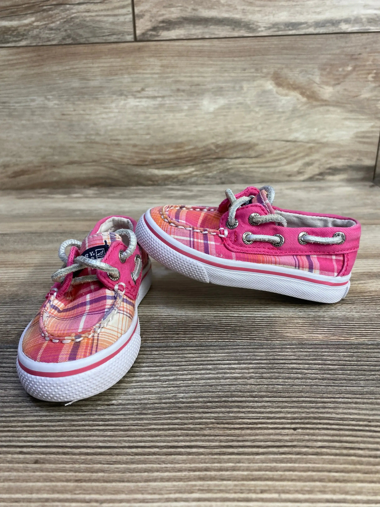 Side and front view of pink plaid Sperry toddler boat shoes with rope laces and white rubber soles on wood background
