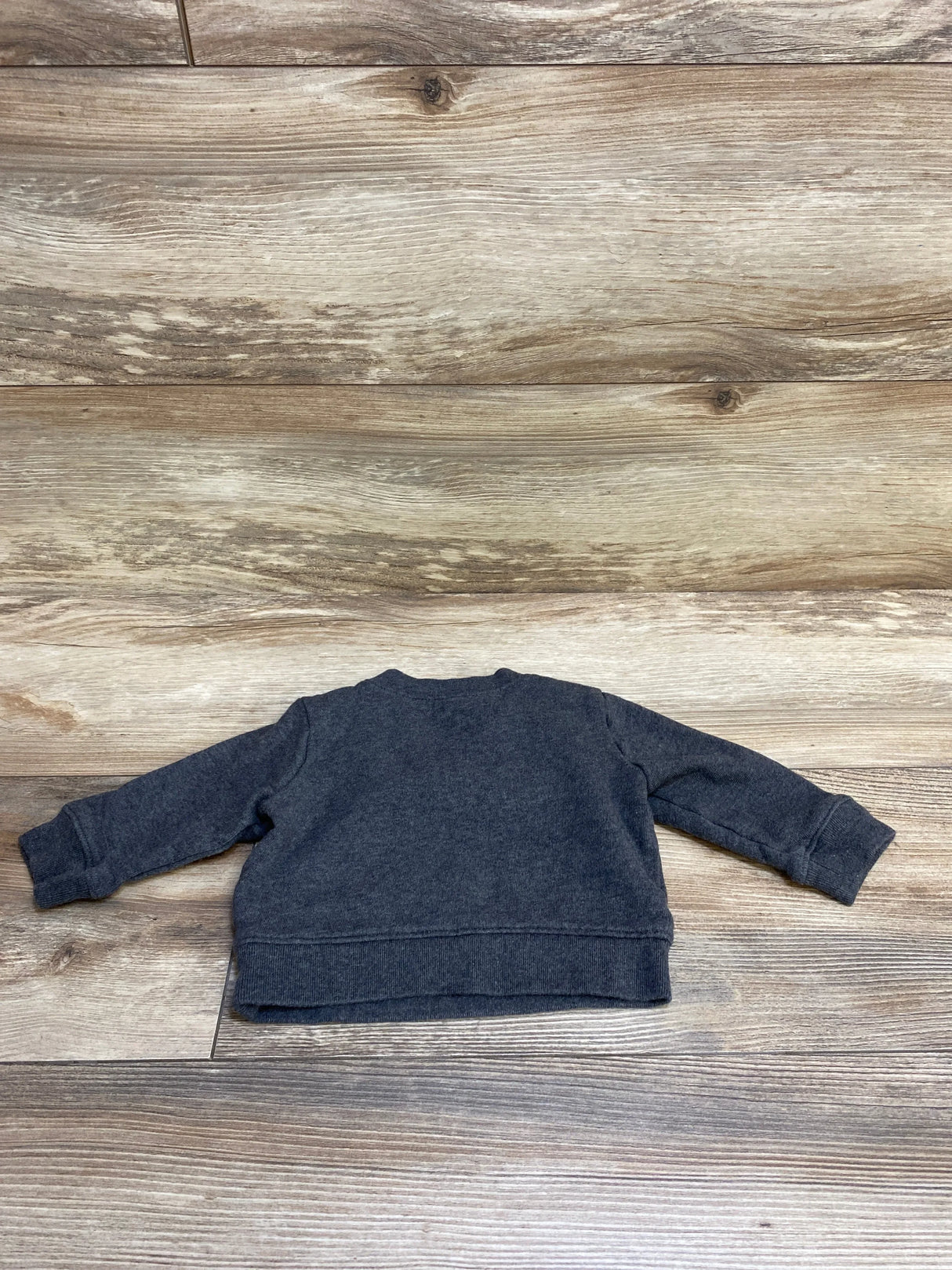 Back view of a dark gray long-sleeve toddler sweatshirt on wood floor