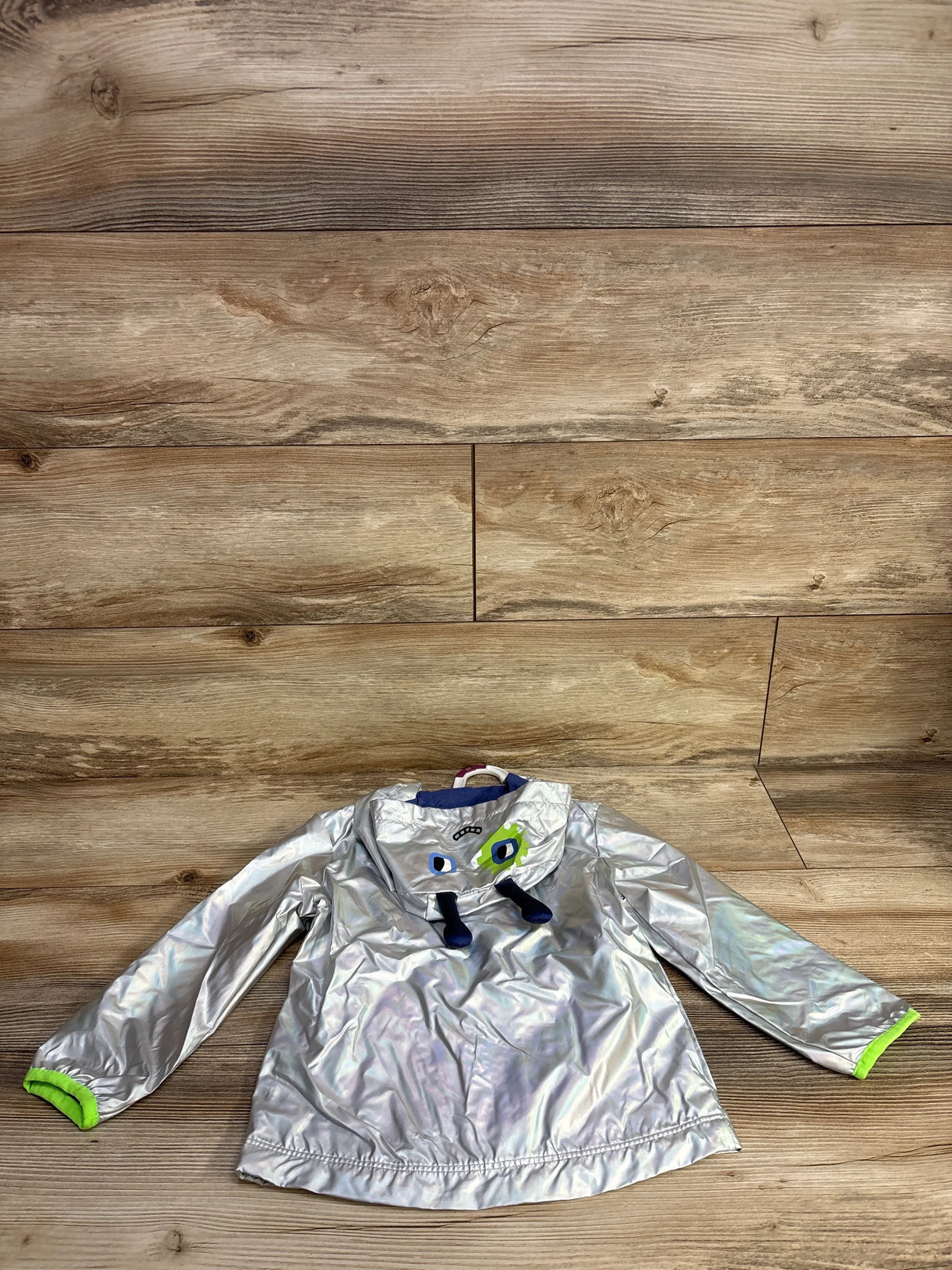 Reflective silver children's jacket with blue and green monster face design on hood, lime green cuffs