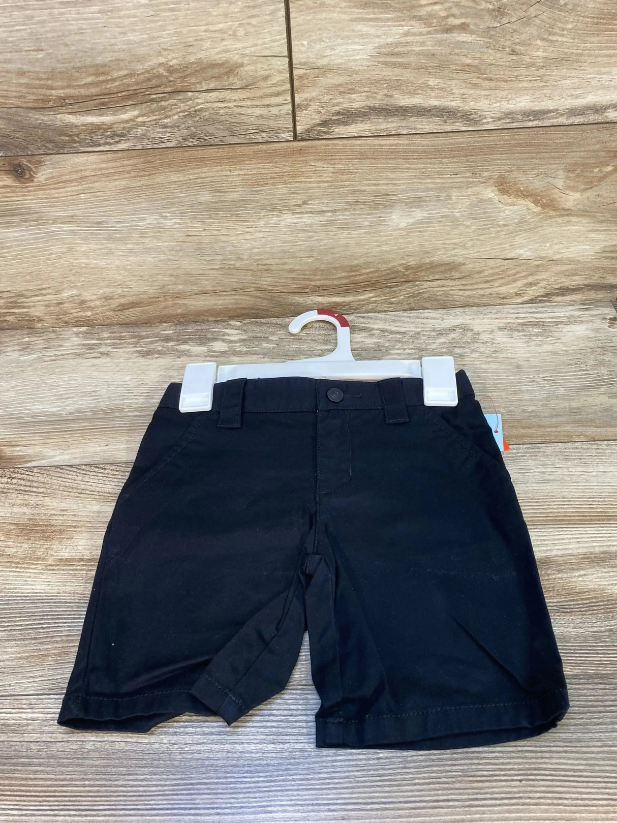 Front view of Cat & Jack black uniform shorts size 4T showing button waist, belt loops and front pockets on wood background