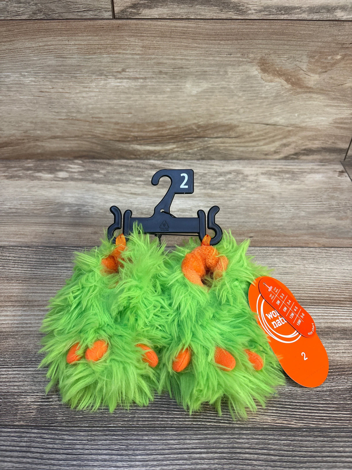 Bright green fuzzy monster baby shoes with orange toes, size 2, on hanger with tag