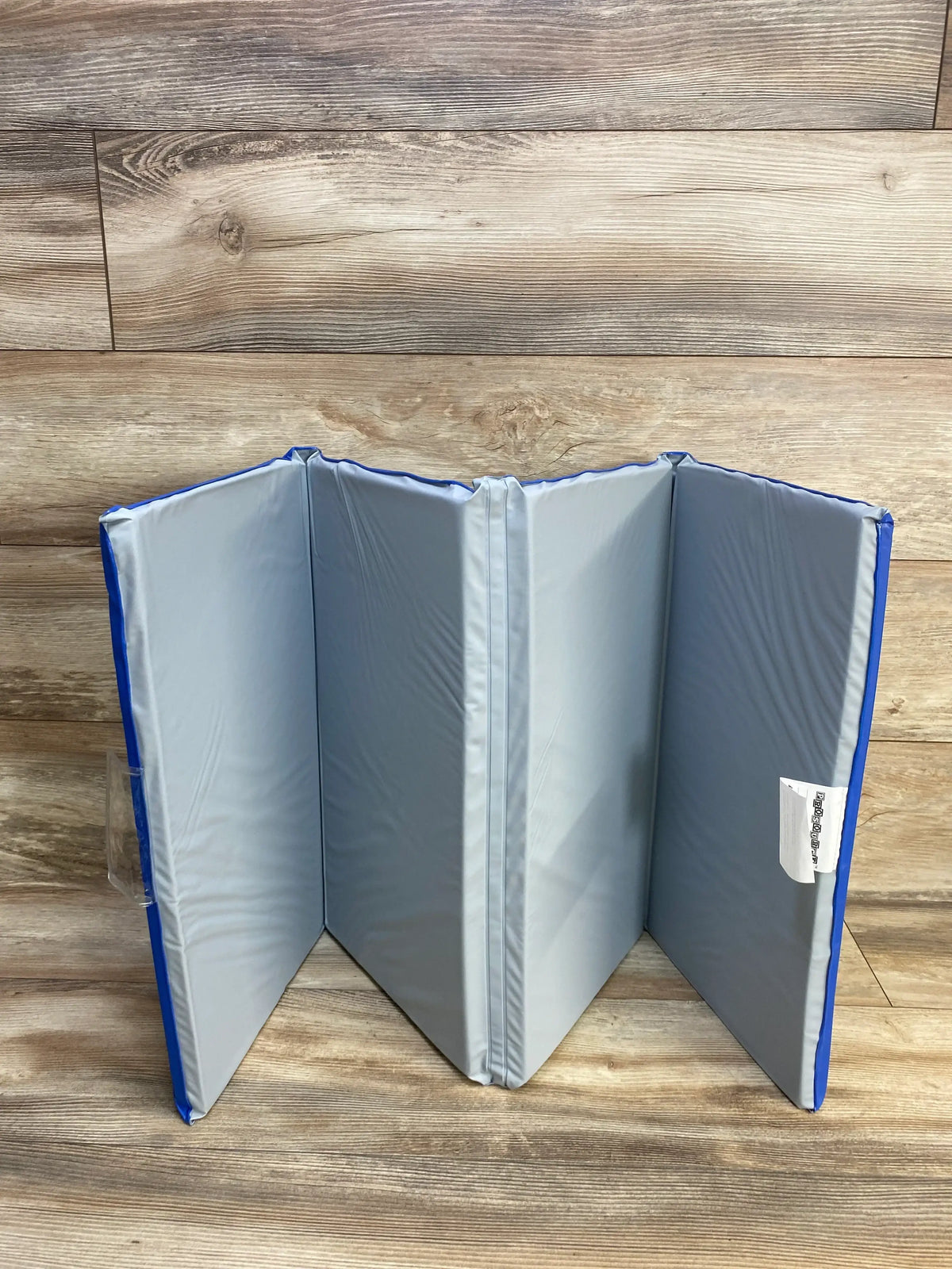 Front view of ProSource Four-Fold Kids Rest Nap Mat showcasing four gray padded panels with blue edging on a wood floor