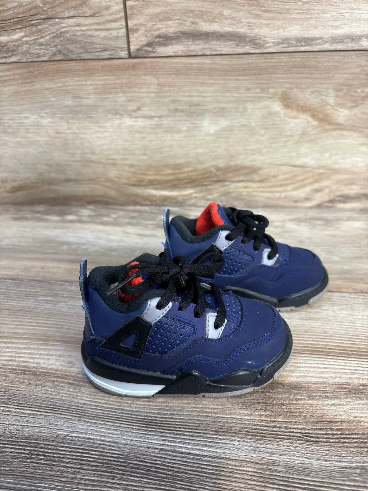 Three-quarter view of Air Jordan 4 Retro Winter TD toddler sneakers in Loyal Blue with black laces on a wood floor