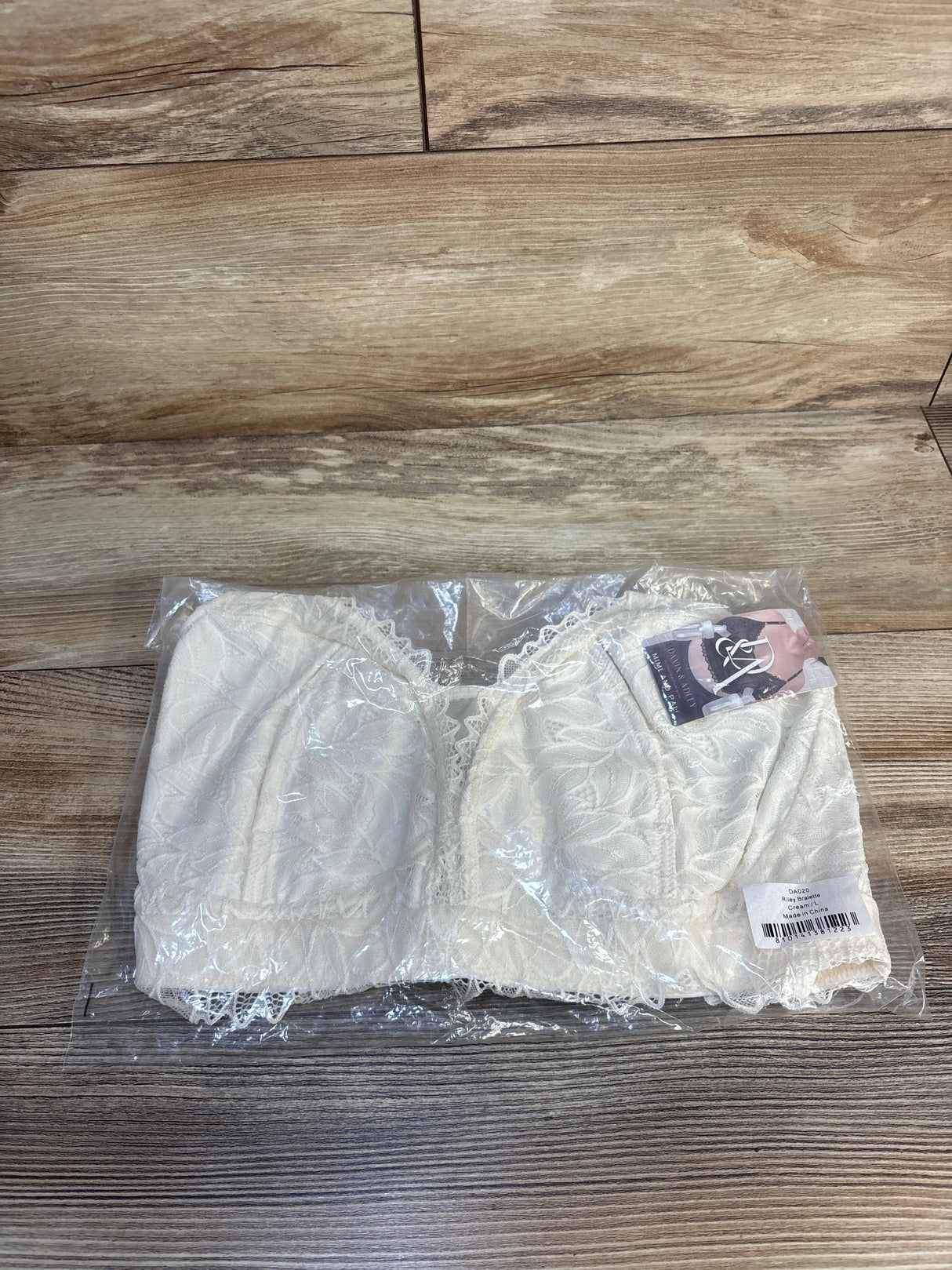 White lace bralette with floral pattern in packaging on wood floor, maternity resale item