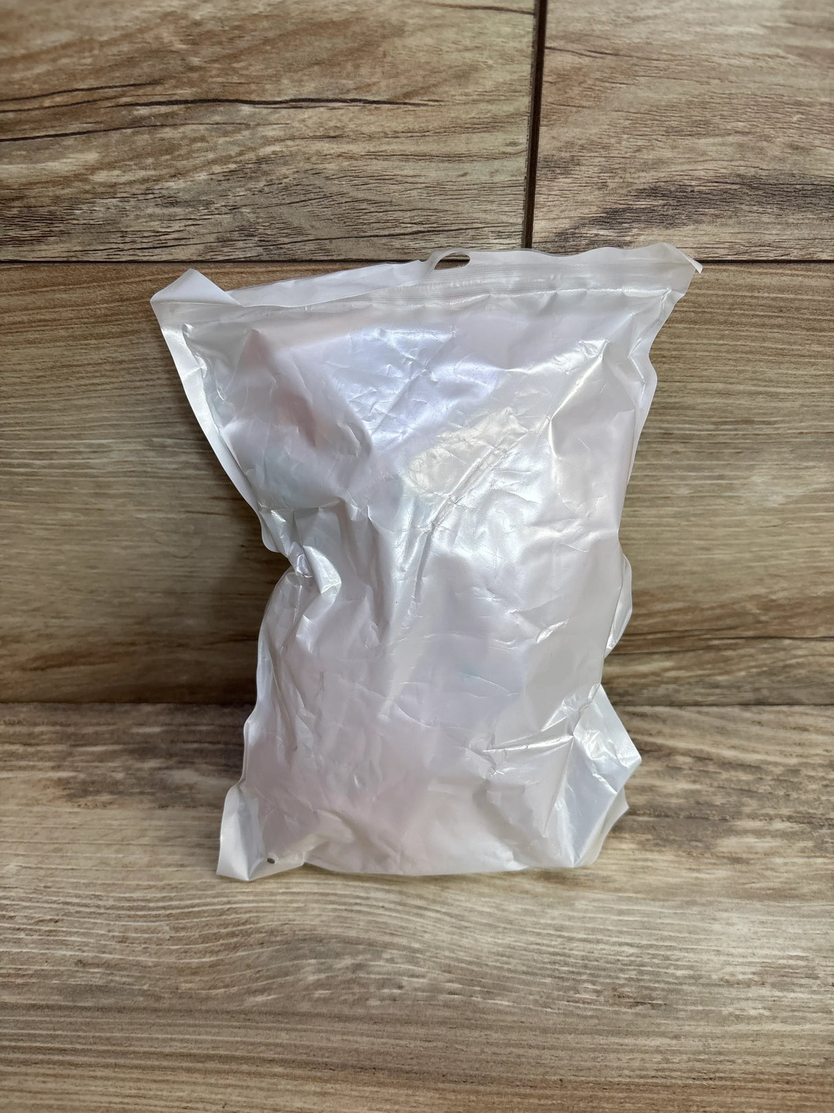 Sealed white vacuum storage bag on wooden surface, suitable for compact kids clothes or baby gear storage