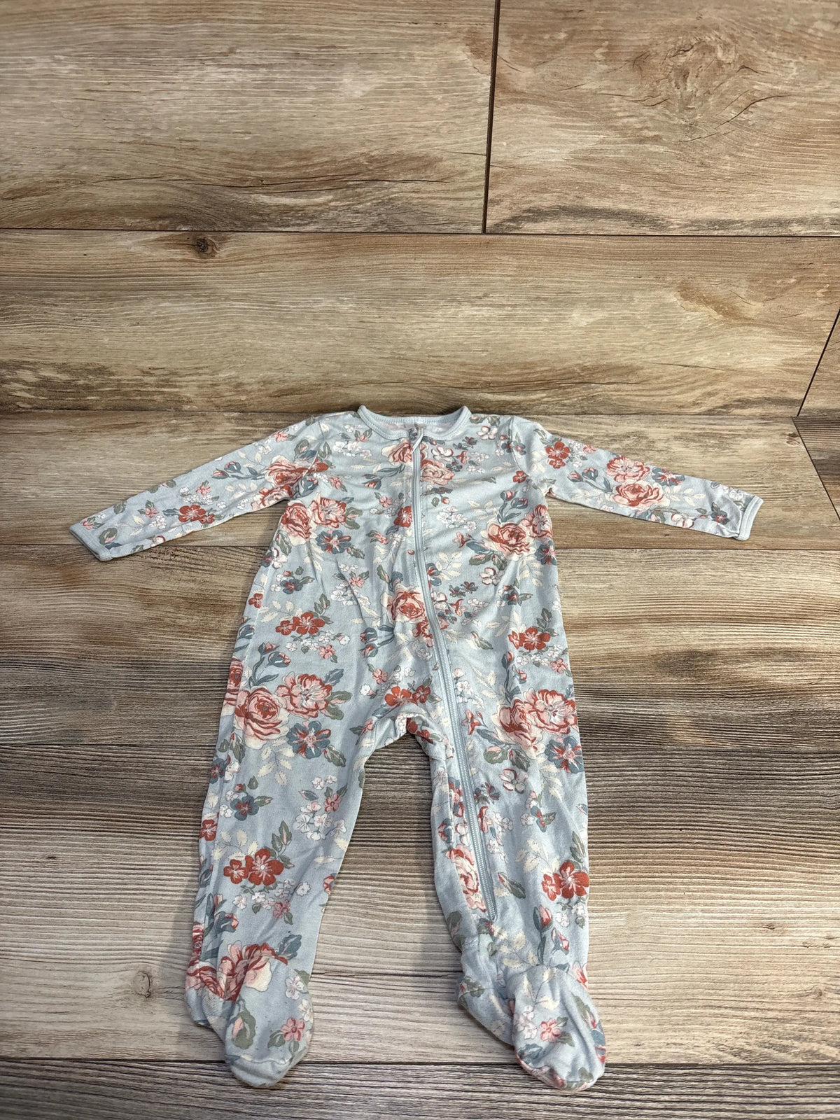 Front view of Modern Moments viscose sleeper showcasing blue floral print, long sleeves, and footed legs on wood flooring
