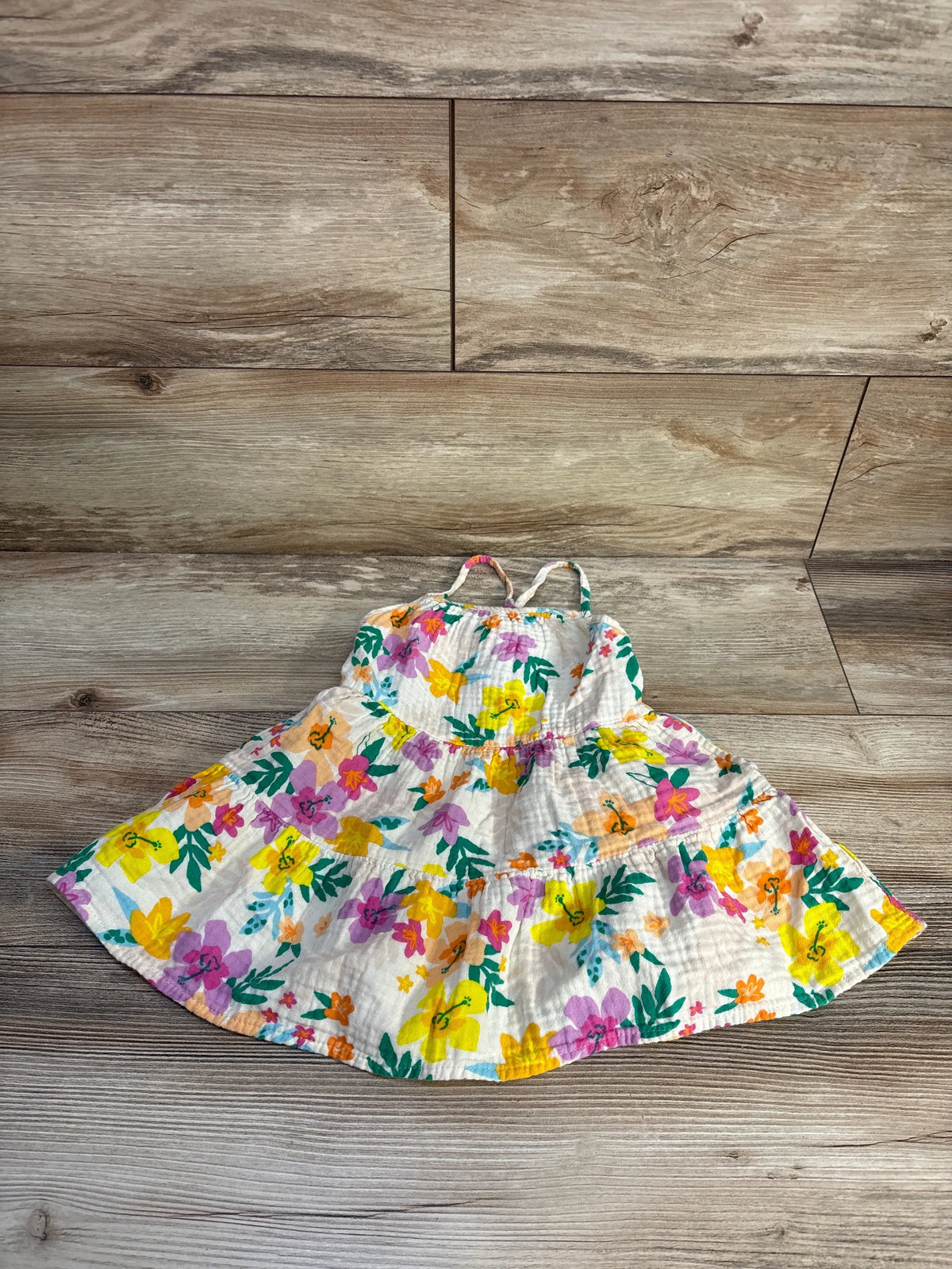 Overhead view of Cat & Jack gauze tank dress in ivory, size 2T, showcasing colorful floral print on wood-grain background
