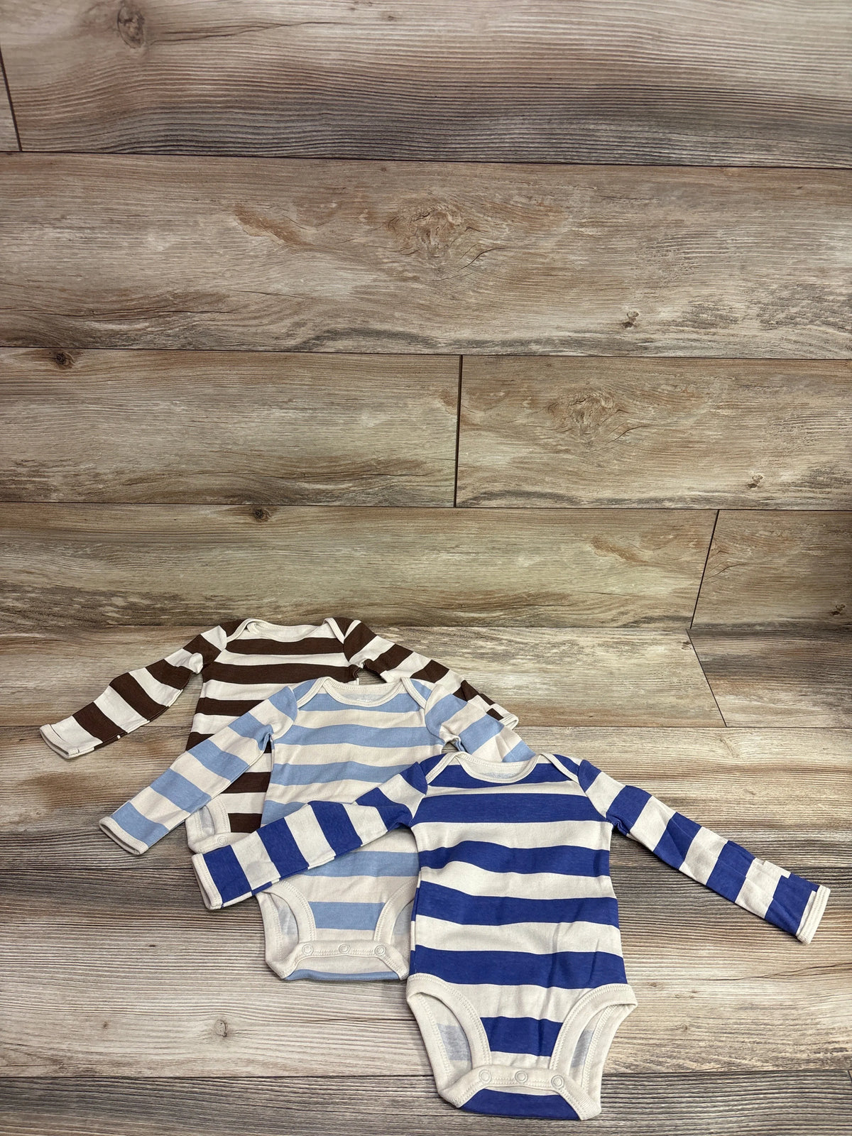 Carter's 3-pack of long-sleeve striped bodysuits in beige, light blue, and dark blue.