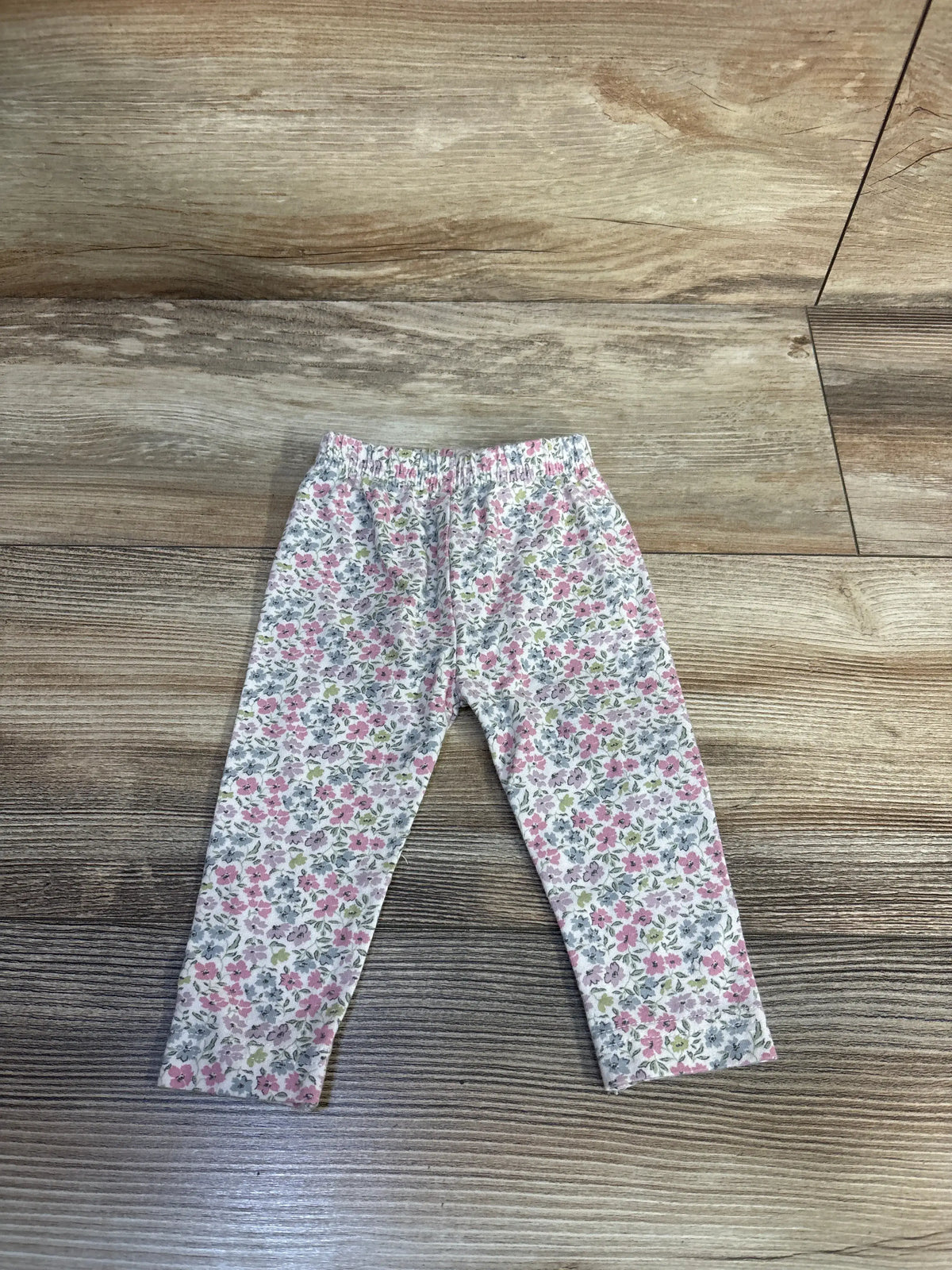 Front view of Jamie Kay floral leggings in newborn size showcasing an elastic waistband and pink floral print on a wood floor