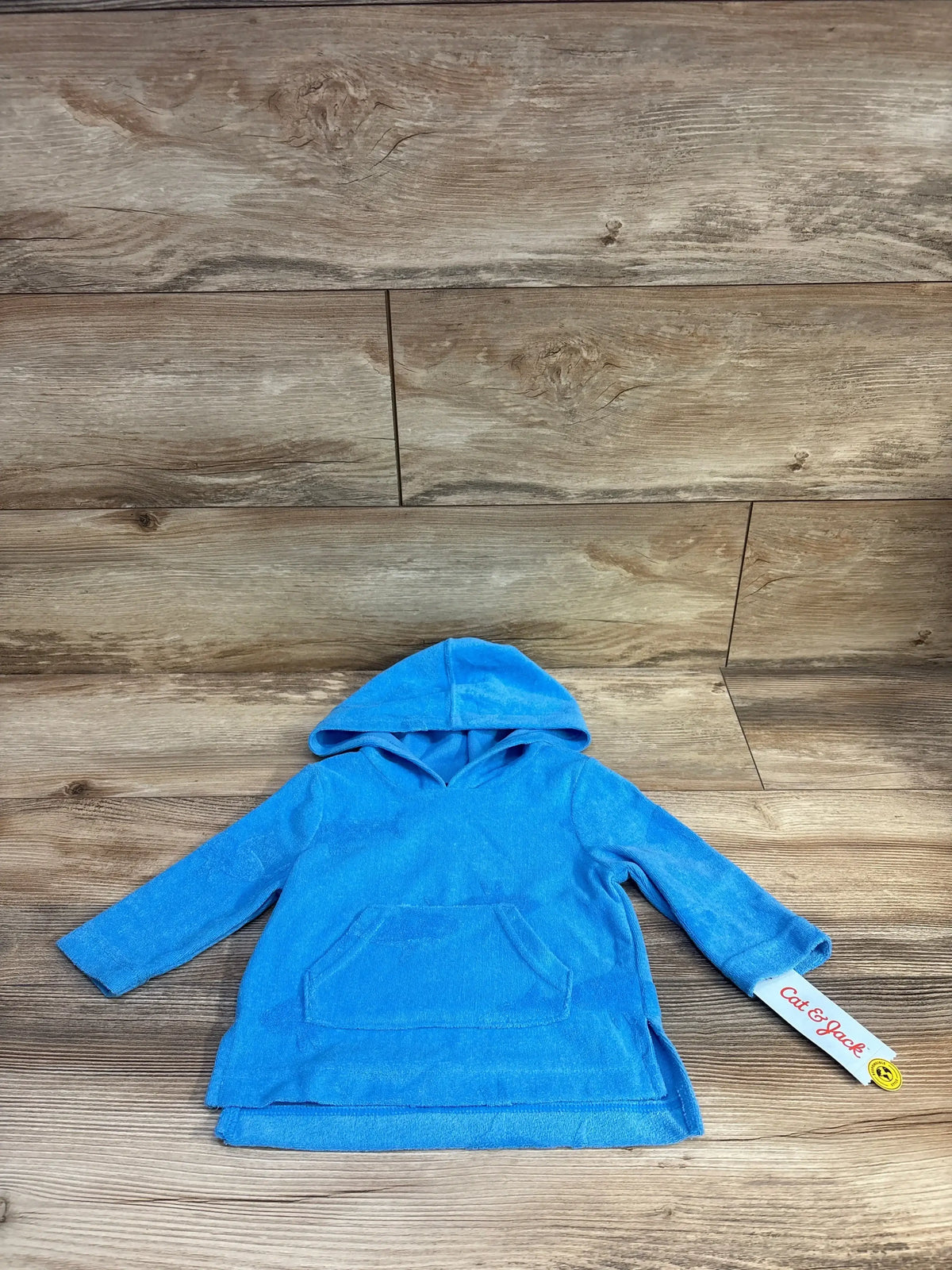 Front flat-lay of blue toddler hooded swim cover-up showcasing kangaroo pocket and terry fabric on wood background