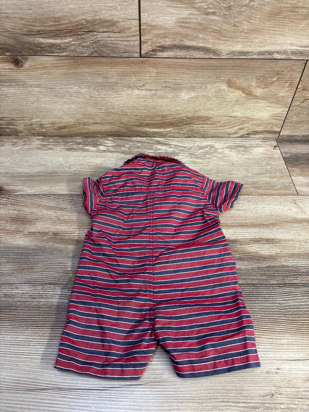 Back view of DKNY striped polo shortie romper in red showcasing horizontal stripes and short sleeves on a wood-look floor