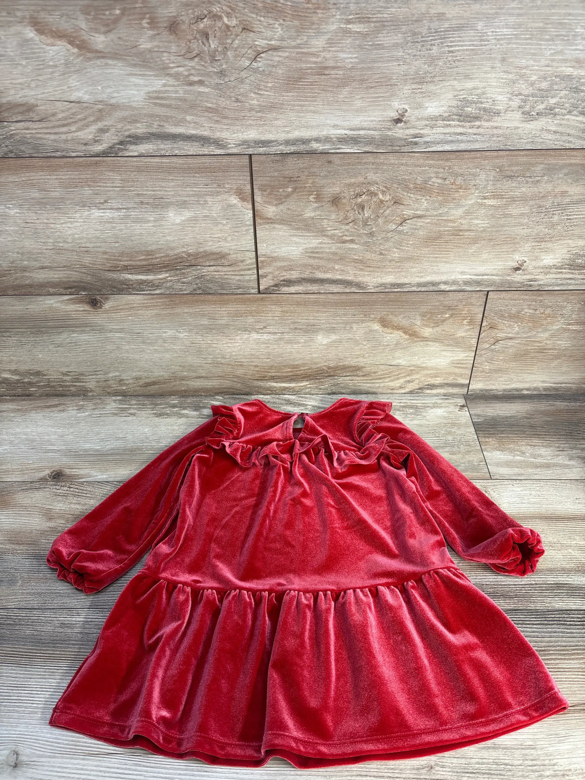 Front view of Cat & Jack red velvet ruffle dress in size 3T showcasing long sleeves and tiered ruffle details with a wood-look floor background