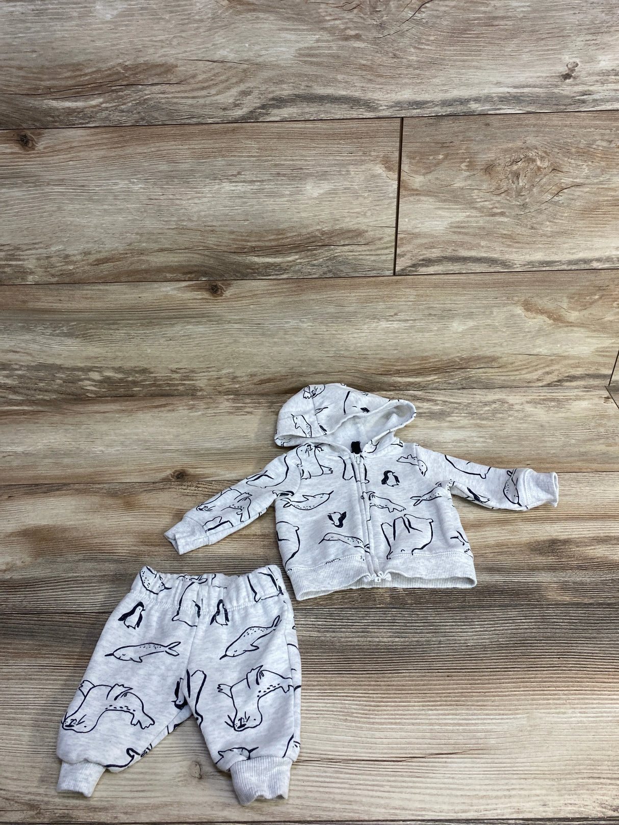 Gray baby outfit with animal print, including zip hoodie and pants on wood background