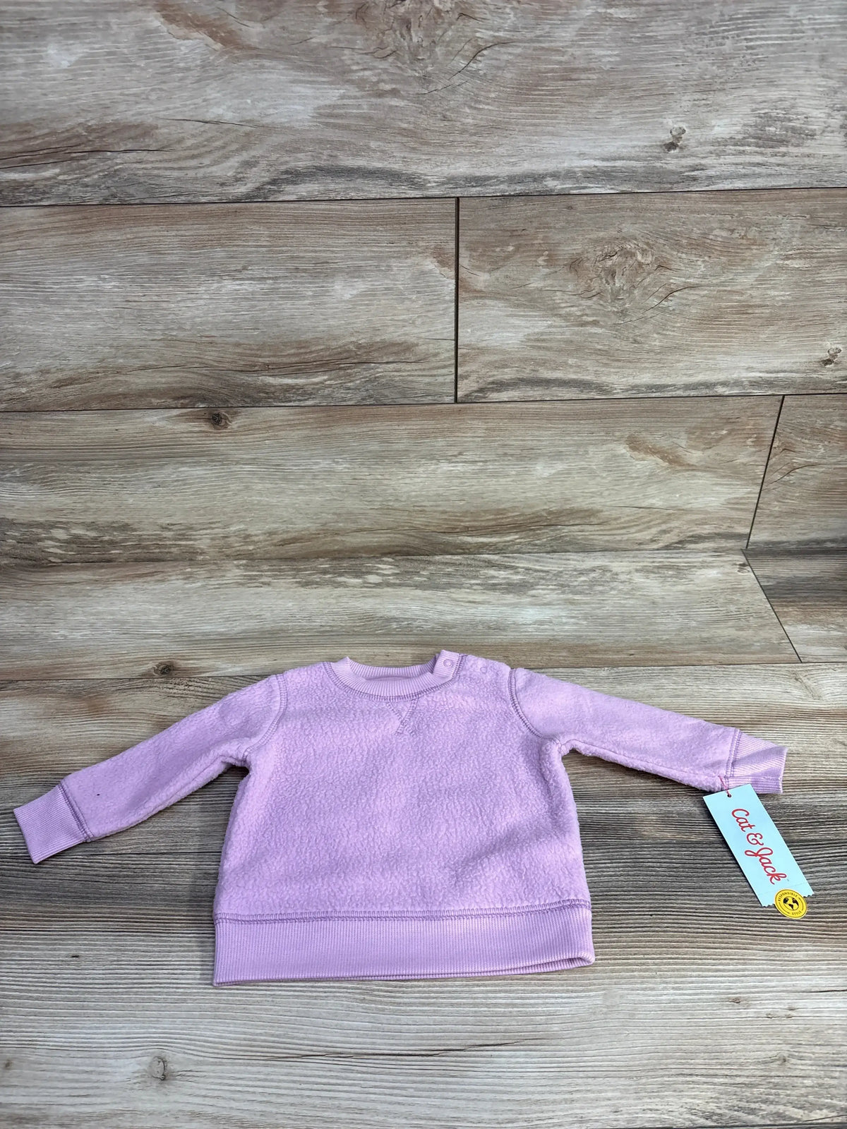 Light purple toddler fleece sweatshirt with long sleeves on wood background, Cat & Jack tag attached