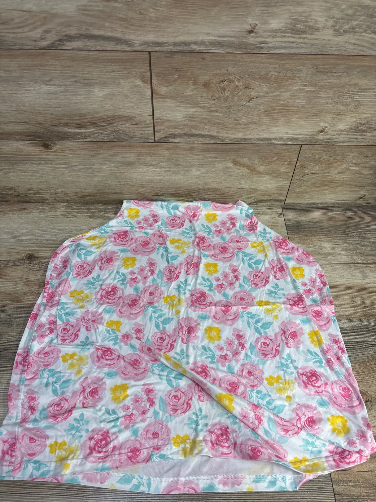 Floral baby blanket with pink, yellow, and teal flowers on white background on wood floor