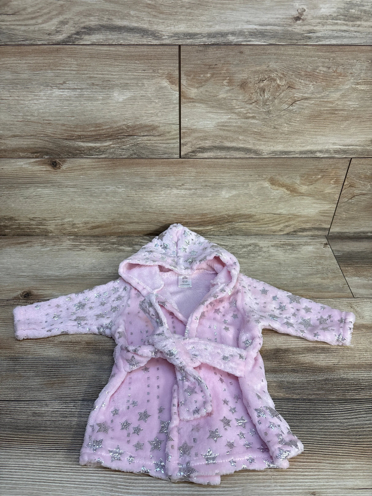 Pink baby robe with silver stars and hood on wood background